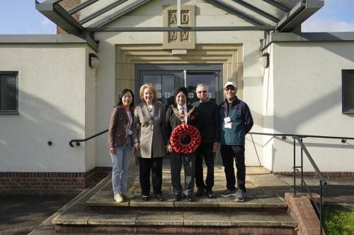 The Mayor of Solihull holds a poppy wreath alongside community representatives