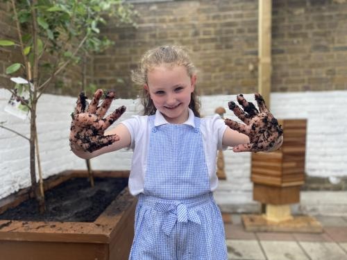 A pupil shows muddy hands while gardening in a photograph promoting Veolia Orchard